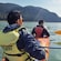 2 men with lifejackets paddling a 2 seat kayak through a body of water